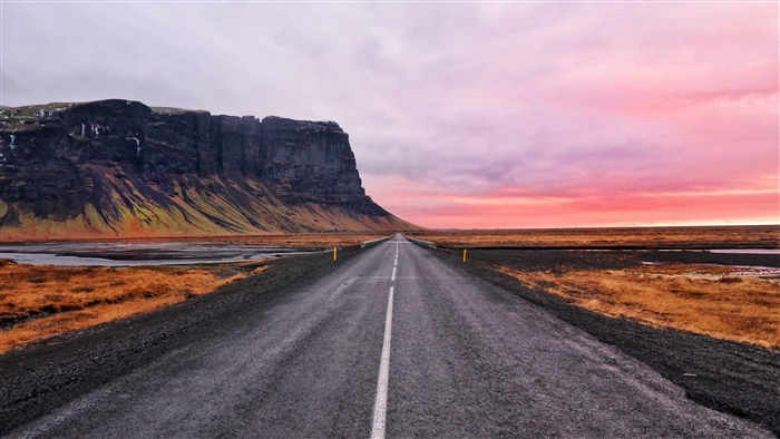 Road through Icelandic landscape with mountains and sunset