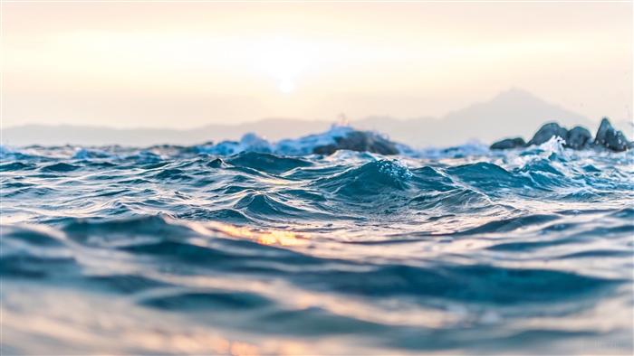 Sea waves with rocks and mountains in the background 4K