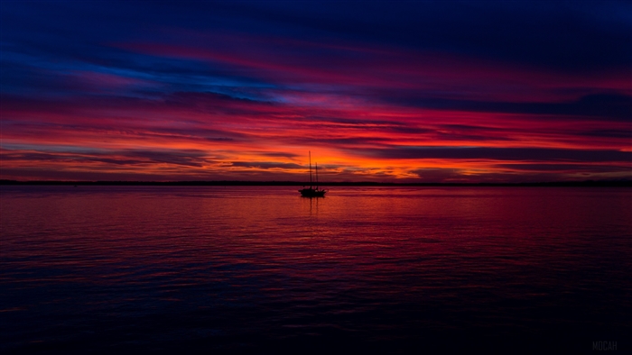 Boat Silhouette at Vibrant Sunset Over Calm Sea