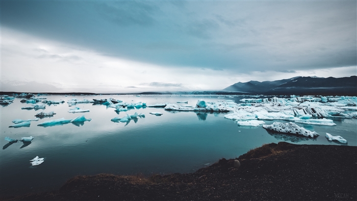 Icebergs floating in a glacial lake with mountains in the background, 4K