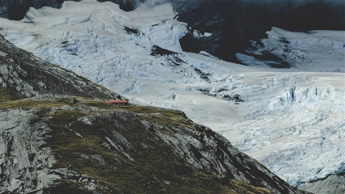 Building on a grassy mountain slope with a glacier in the background 4K
