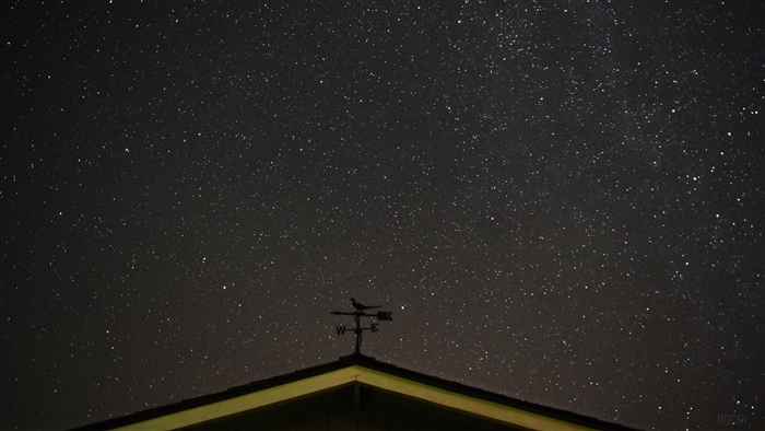Starry sky above a roof with a weather vane
