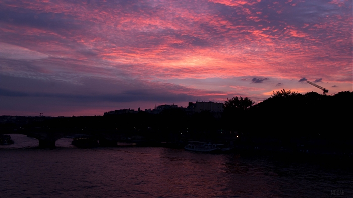 Sunset over a river with city skyline and crane