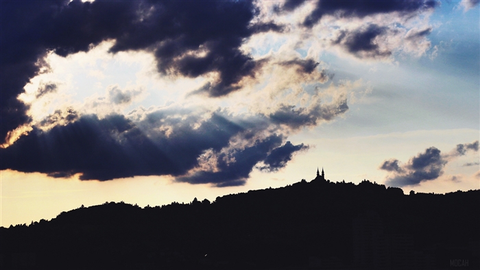 Silhouette of a castle on a hill with dramatic clouds
