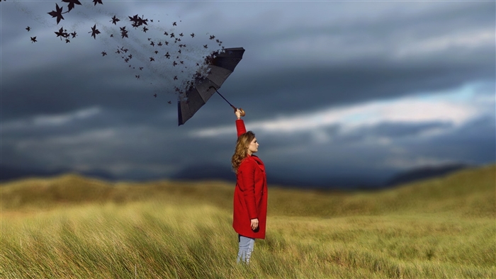 Woman with dissolving umbrella in field
