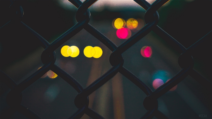 Bokeh lights seen through a chain-link fence