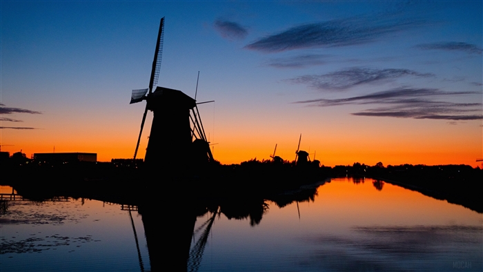 Windmills silhouette at sunset over river 4K