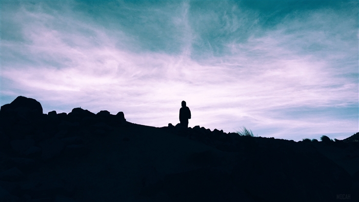 Silhouette of a person on a hill under a cloudy sky 4K