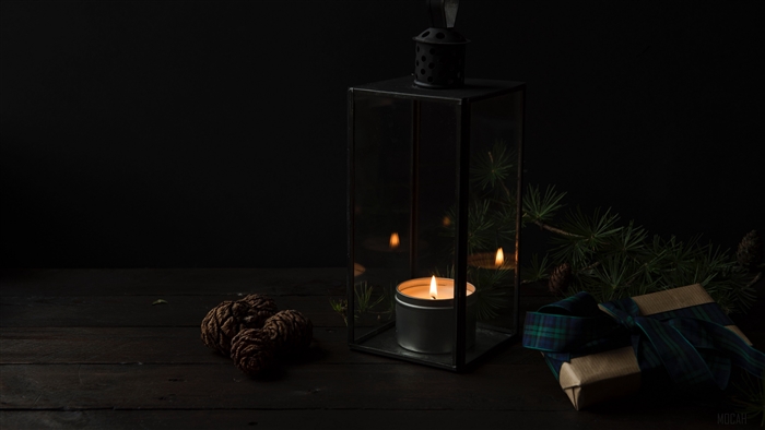 Candle in a lantern with pine cones and gift