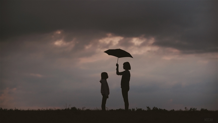 Two silhouettes under an umbrella at dusk