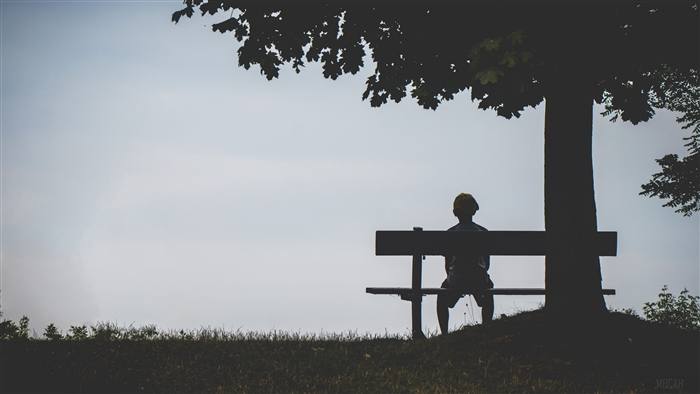 Silhouette of a Child Sitting Alone on a Bench