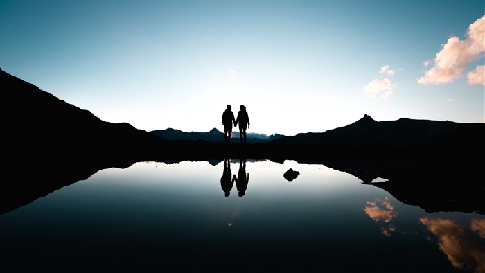 Couple holding hands at sunset with reflection
