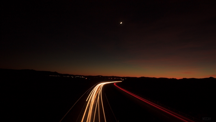 Long exposure of highway lights at dusk with moon