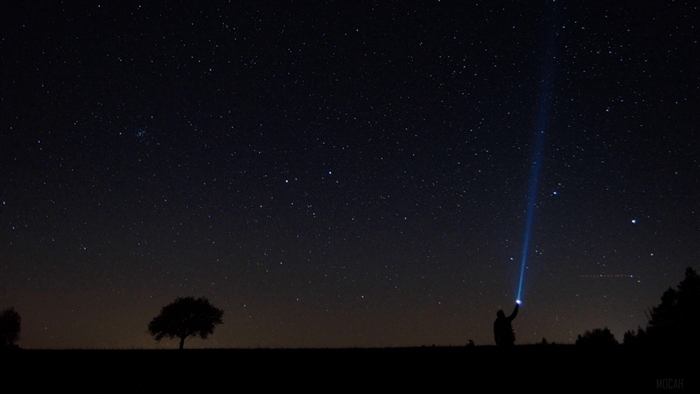 Man with flashlight under starry sky