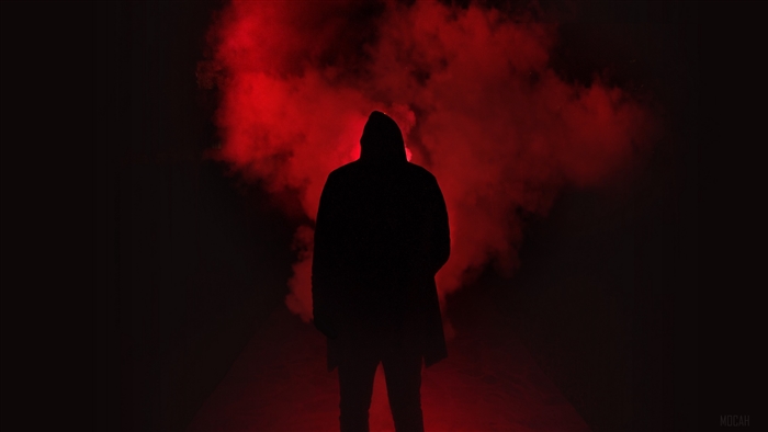 Silhouette of a person in a hood with red smoke