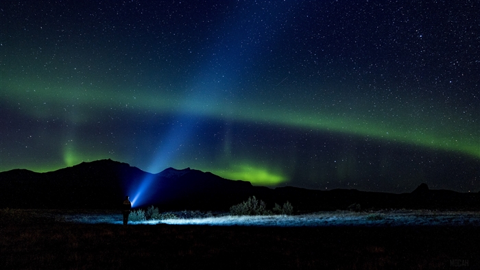 Man with flashlight under Northern Lights 4K