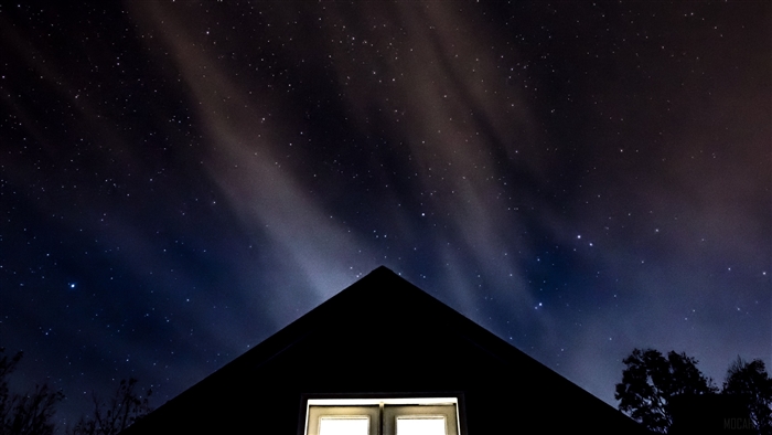 Starry sky over a house roof with a window