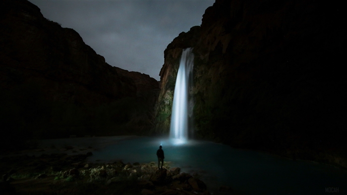 Man with headlamp at waterfall at night