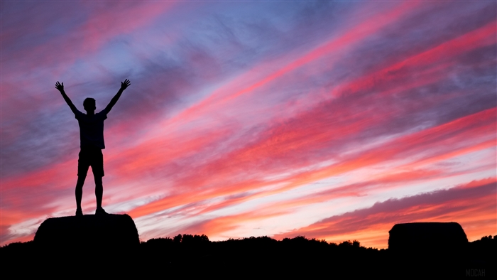 Man silhouetted against a colorful sunset sky
