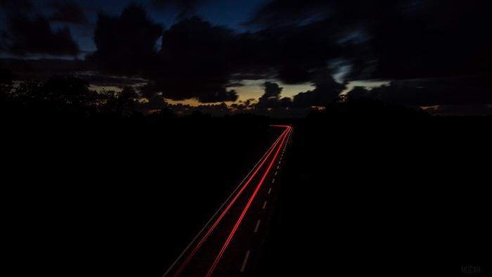 Road at night with light trails and dark sky