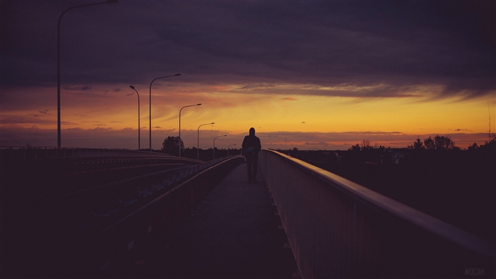 Man walking on a bridge at sunset