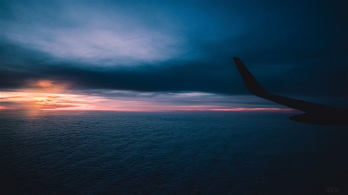 Airplane wing over clouds at sunset 4K