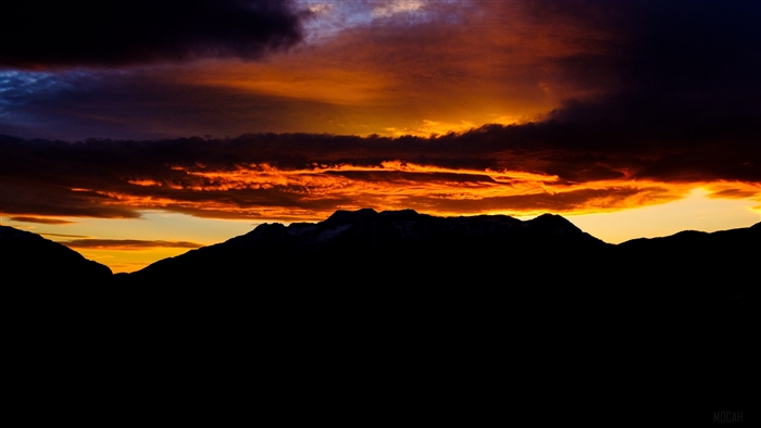 Dark mountains silhouette against a vibrant sunset sky with clouds 4K