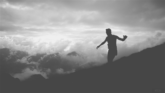 Man running on a mountain with clouds and mountains in the background, BW 4K