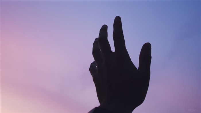 Silhouette of a hand reaching towards the sky