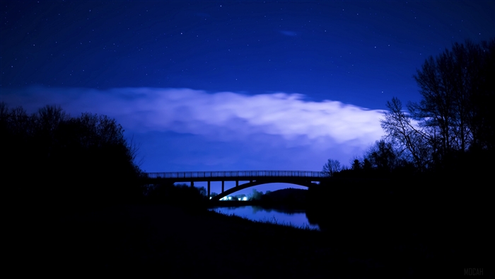 Bridge at night under a starry sky with clouds