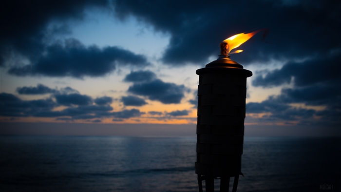 Torch with flame at dusk over the ocean