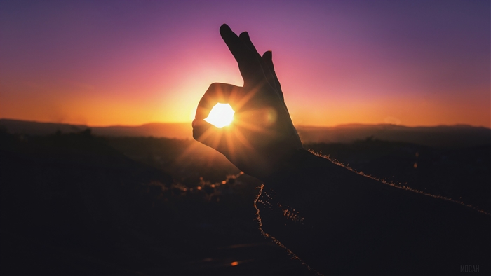 Hand making OK sign with sun during sunset 4K