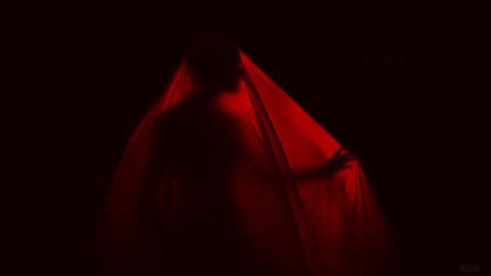 Silhouette of a man behind red fabric in dark 4K