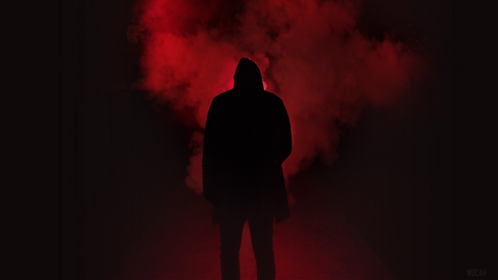 Silhouette of a man in a hood with red smoke