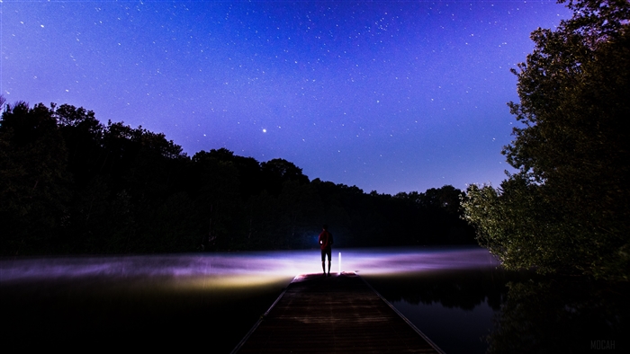 Person on dock under starry sky with fog