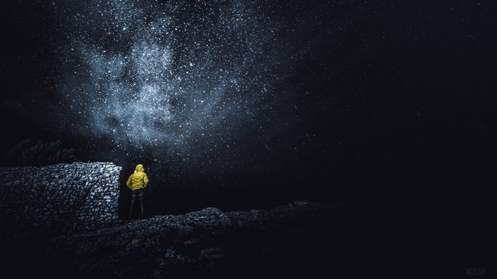 Man in yellow jacket looking at starry sky