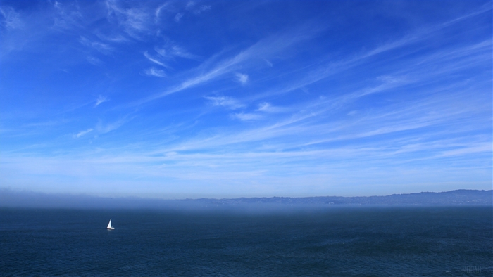 Sailboat on the sea under a blue sky with clouds