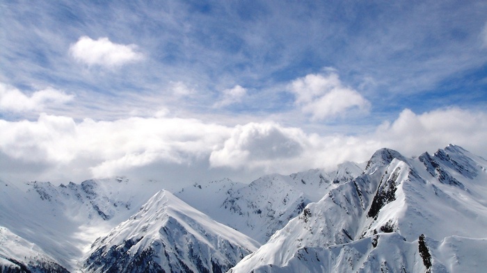 Snowy mountain peaks under a cloudy blue sky