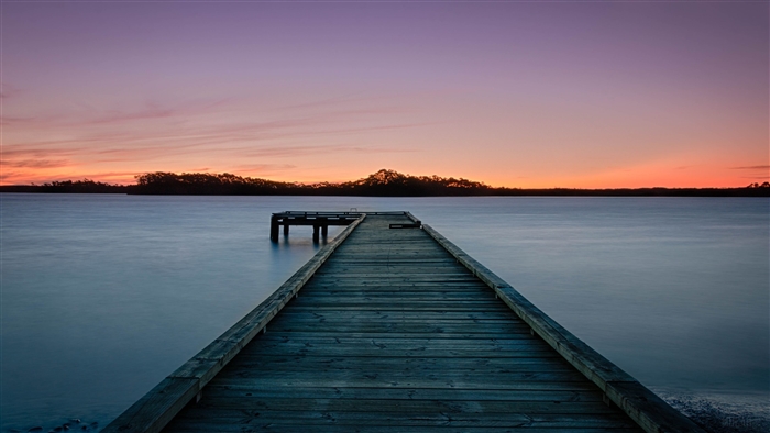 Sunset over water with a wooden pier
