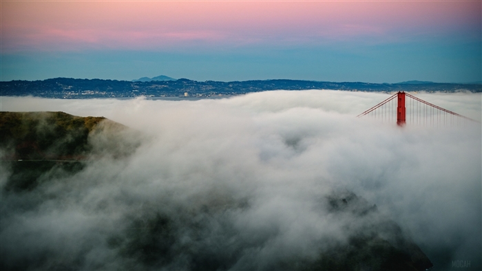 Golden Gate Bridge shrouded in fog at sunrise