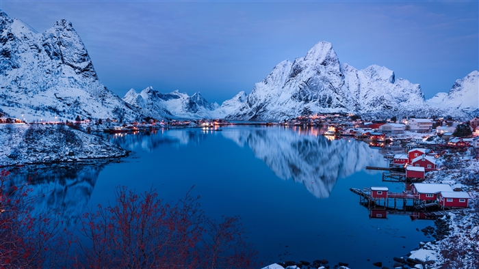 Winter village with snow-capped mountains and reflection