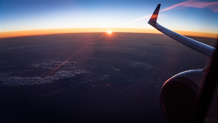 Airplane wing over clouds at sunset 4K
