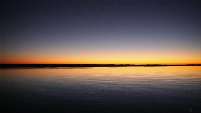 Sunset over a calm sea with a distant shoreline