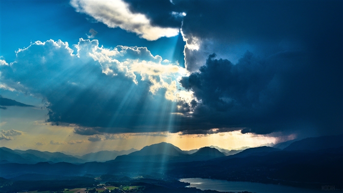 Sunbeams through clouds over mountains and lake