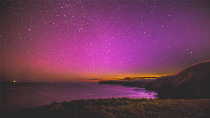 Pink and purple starry sky over the ocean and cliffs
