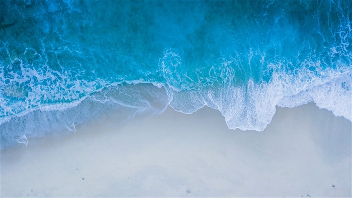Aerial view of ocean waves crashing on a sandy beach