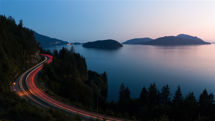 Highway with light trails at dusk overlooking islands