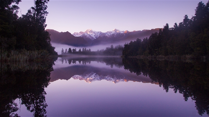 Lake Matheson at sunrise with snow-capped mountains