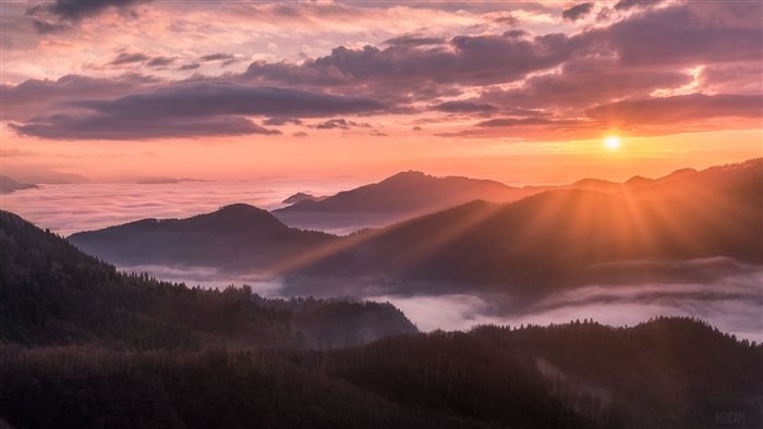 Sunrise over misty mountains with sunbeams