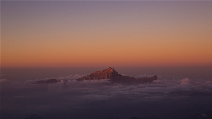 Mountain peak emerging from clouds at sunset 4K